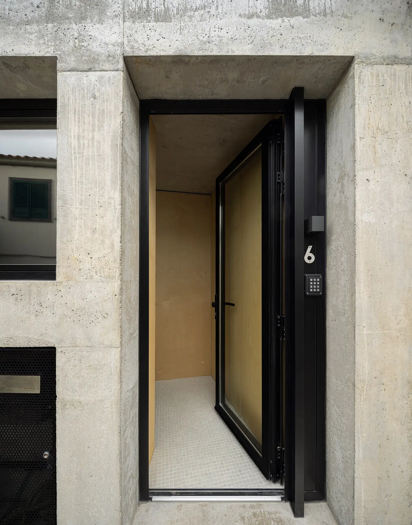 The open front door of an SO Arquitetos house, set deep in board-marked concrete
